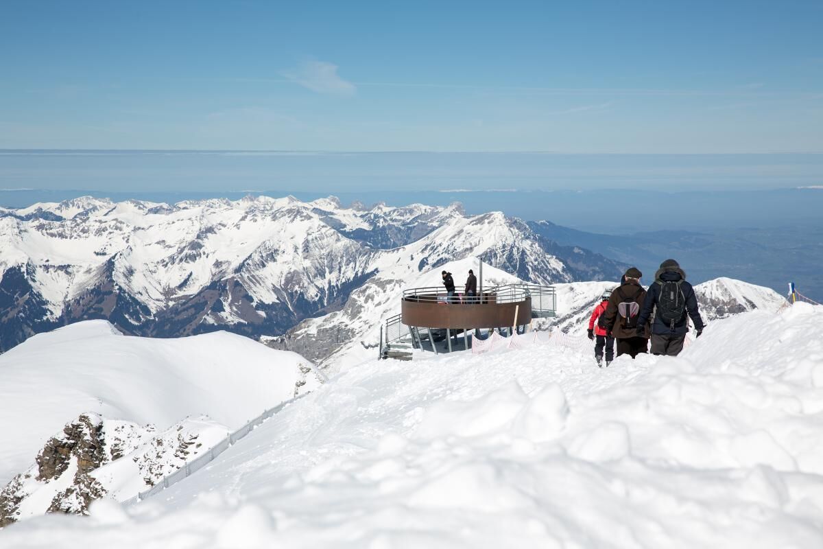 A snow-covered mountain with a viewing platform and a clear sky.