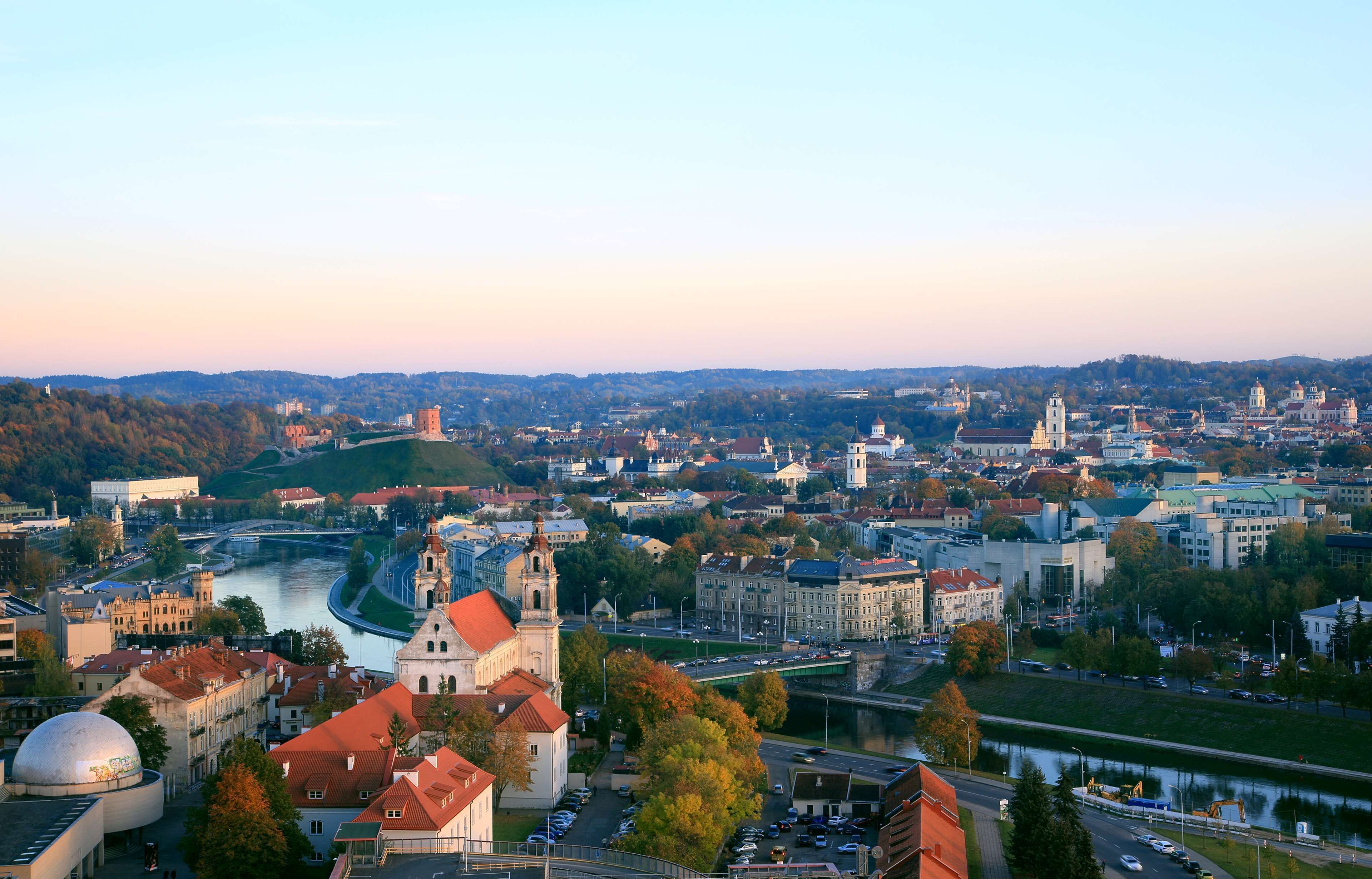 Vista panorámica de una ciudad con un río, edificios históricos y una imponente torre de iglesia.