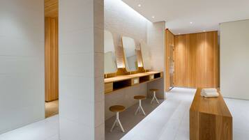 A modern bathroom with wooden accents, a vanity with mirrors, and a bench.