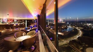 A modern bar area with seating and a city view. - Radisson Blu Hotel Lietuva (Vilnius)