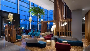 A modern lobby with a large glass wall, wooden partitions, and various seating areas. - Radisson Blu Hotel Lietuva (Vilnius)