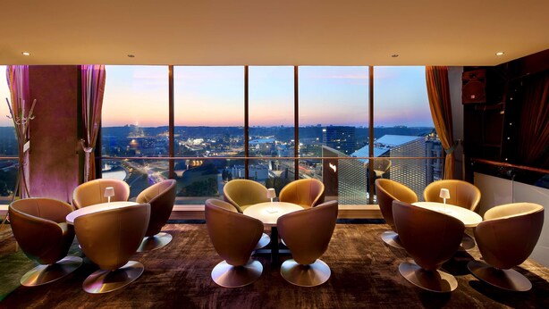 A modern room with a large window, a round table, and six chairs. - Radisson Blu Hotel Lietuva (Vilnius)
