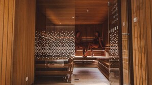 A sauna with wooden benches and a glass wall with circular patterns. - Radisson Blu Hotel Lietuva (Vilnius)