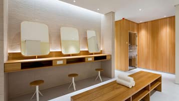 Relax in this serene bathroom with a large mirror, stools, and a bench.