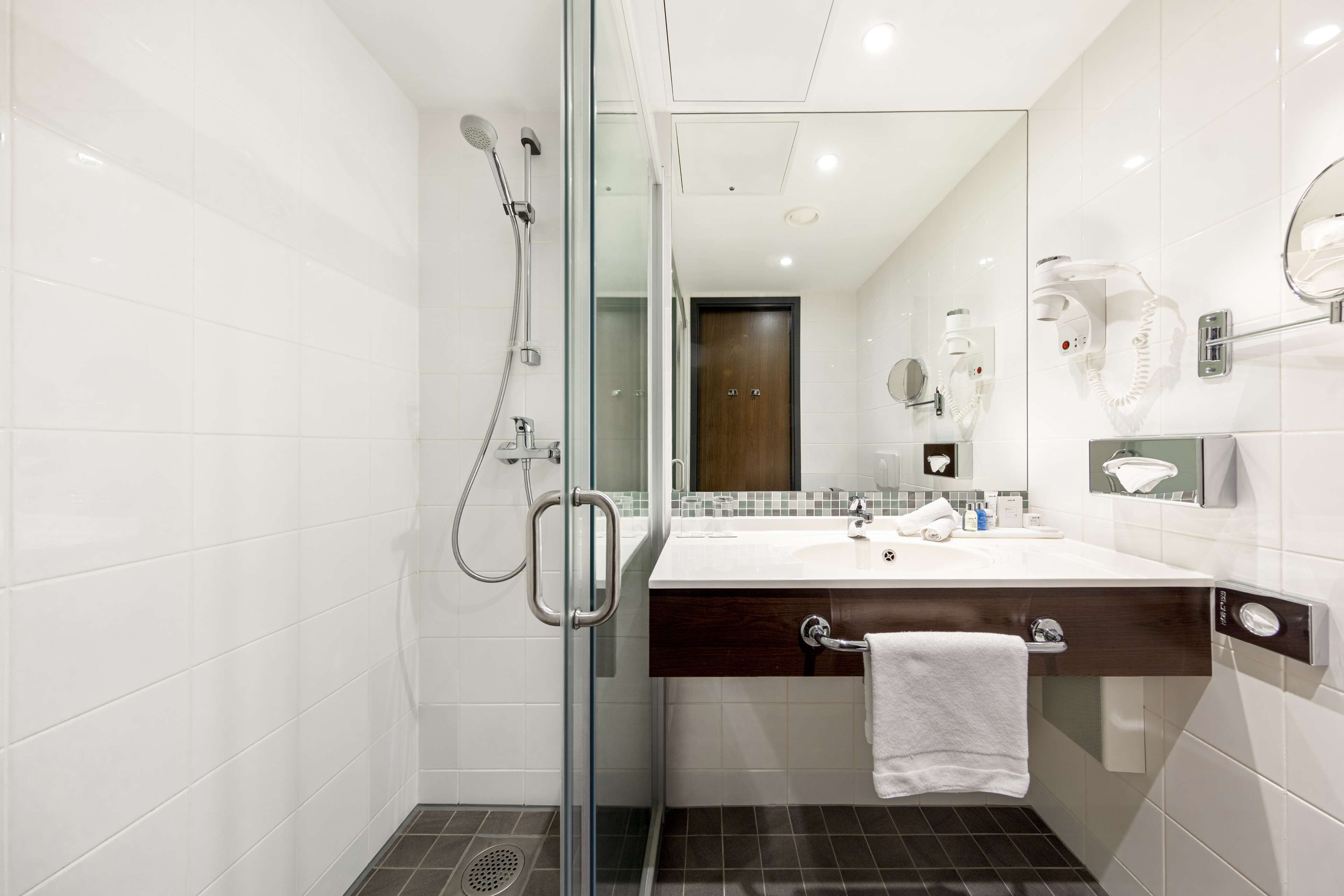 A modern bathroom with a glass shower enclosure, a vanity with a mirror, and a towel rack.