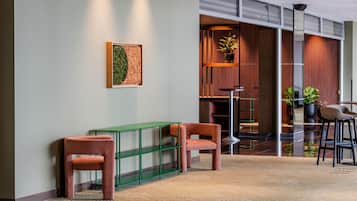 Un hall d’entrée moderne avec un canapé vert, une petite table et un espace salon doté d’un bar.