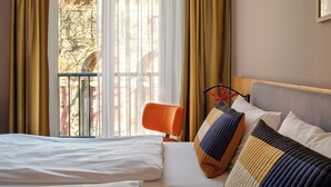 Una habitación de hotel con una cama grande, una silla y una ventana con cortinas.