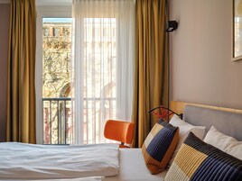 Camera d'albergo con un letto grande, una sedia e una finestra con tende.