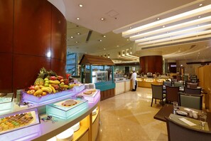 A buffet area with a variety of food items and a chef preparing food. - B P International (Kowloon)