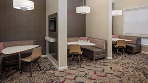 A modern hotel room with a seating area featuring a sofa and a table, a television mounted on the wall, and a patterned carpet. - Residence Inn by Marriott Tucson Williams Centre (Tucson)