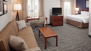 A hotel room with a sofa, a desk with a television, a bed, and a carpeted floor. - Residence Inn by Marriott Tucson Williams Centre (Tucson)