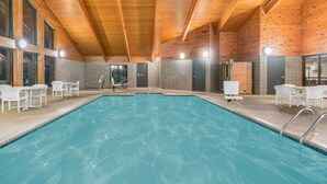 An indoor swimming pool with wooden beams and white chairs around it. - Baymont by Wyndham Kasson Rochester Area (Kasson)