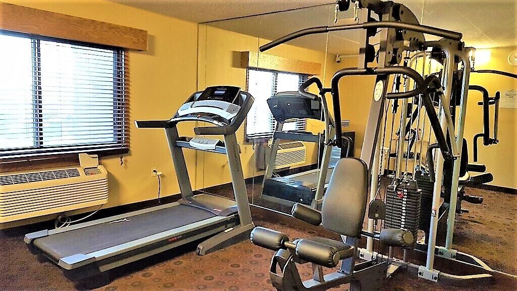 A fitness center with treadmills, a weight machine, and a mirrored wall.