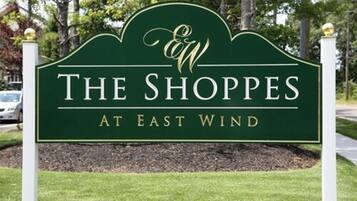 Placa para 'The Shops at East Wind', com fundo verde e letras douradas.