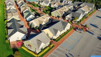 An aerial view of a residential area with houses, a parking lot, and a green space.