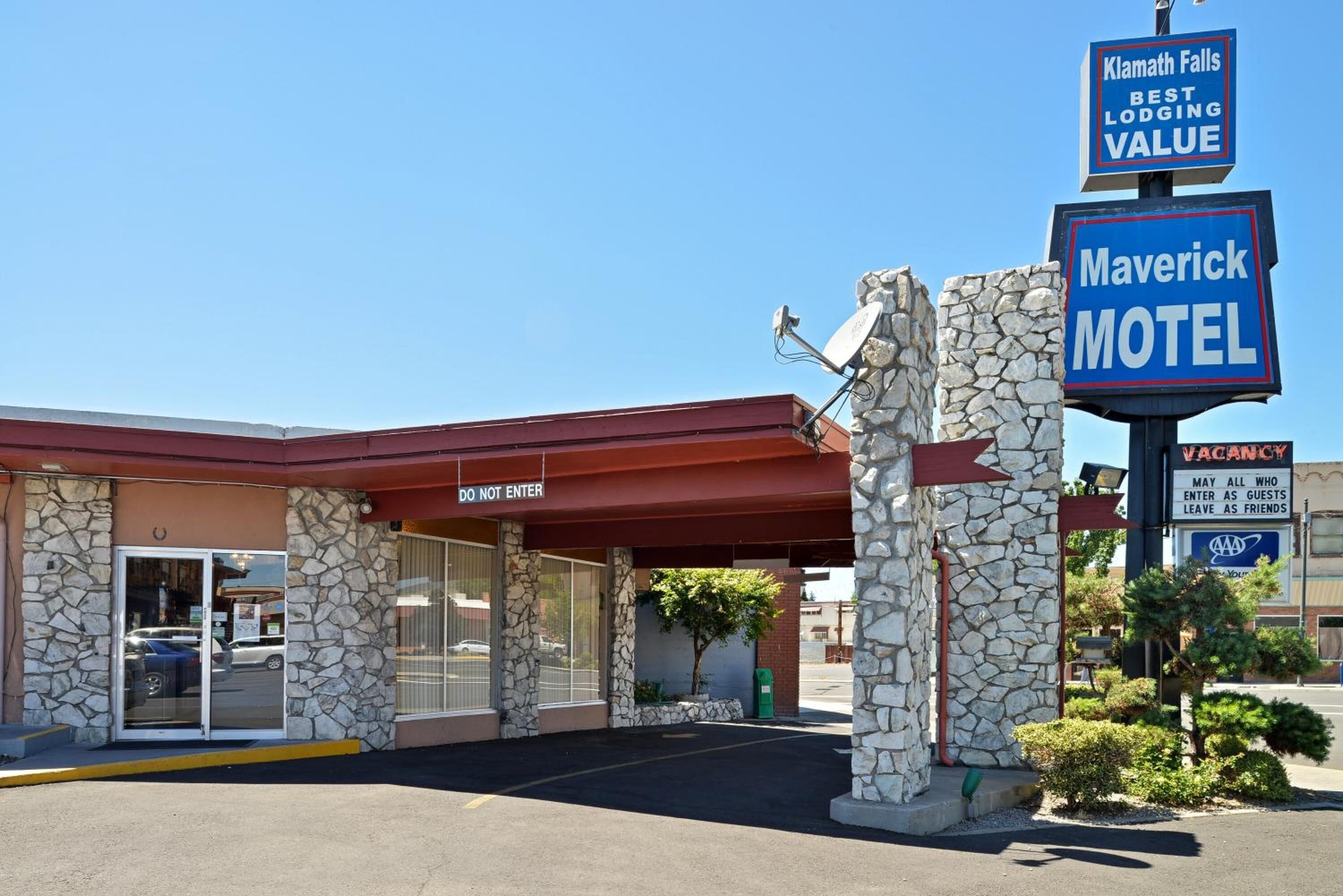 A motel with a stone facade, a red awning, and a 'VACANCY' sign.