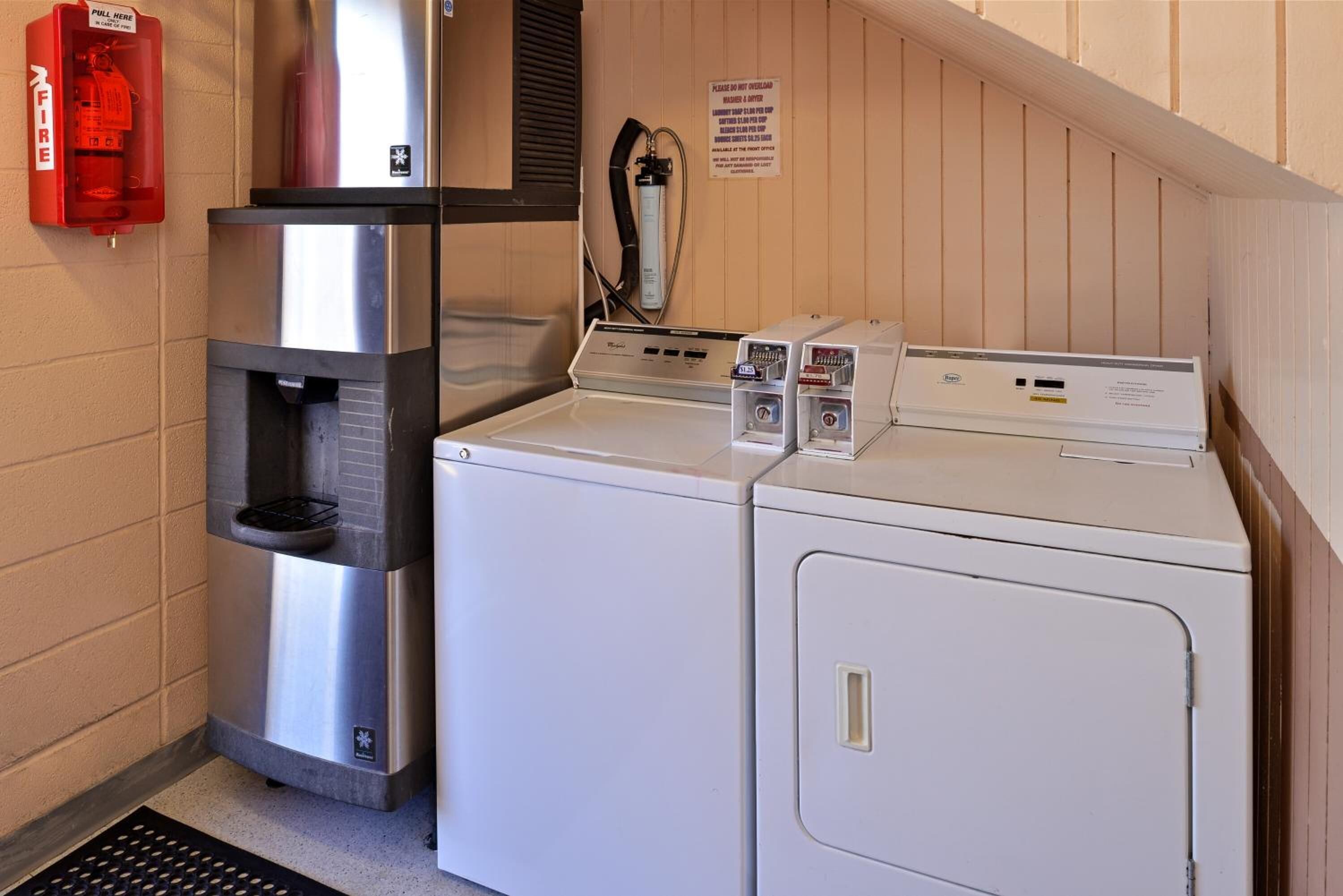 A laundry area with a stainless steel water dispenser, a fire extinguisher, and a sign with instructions.