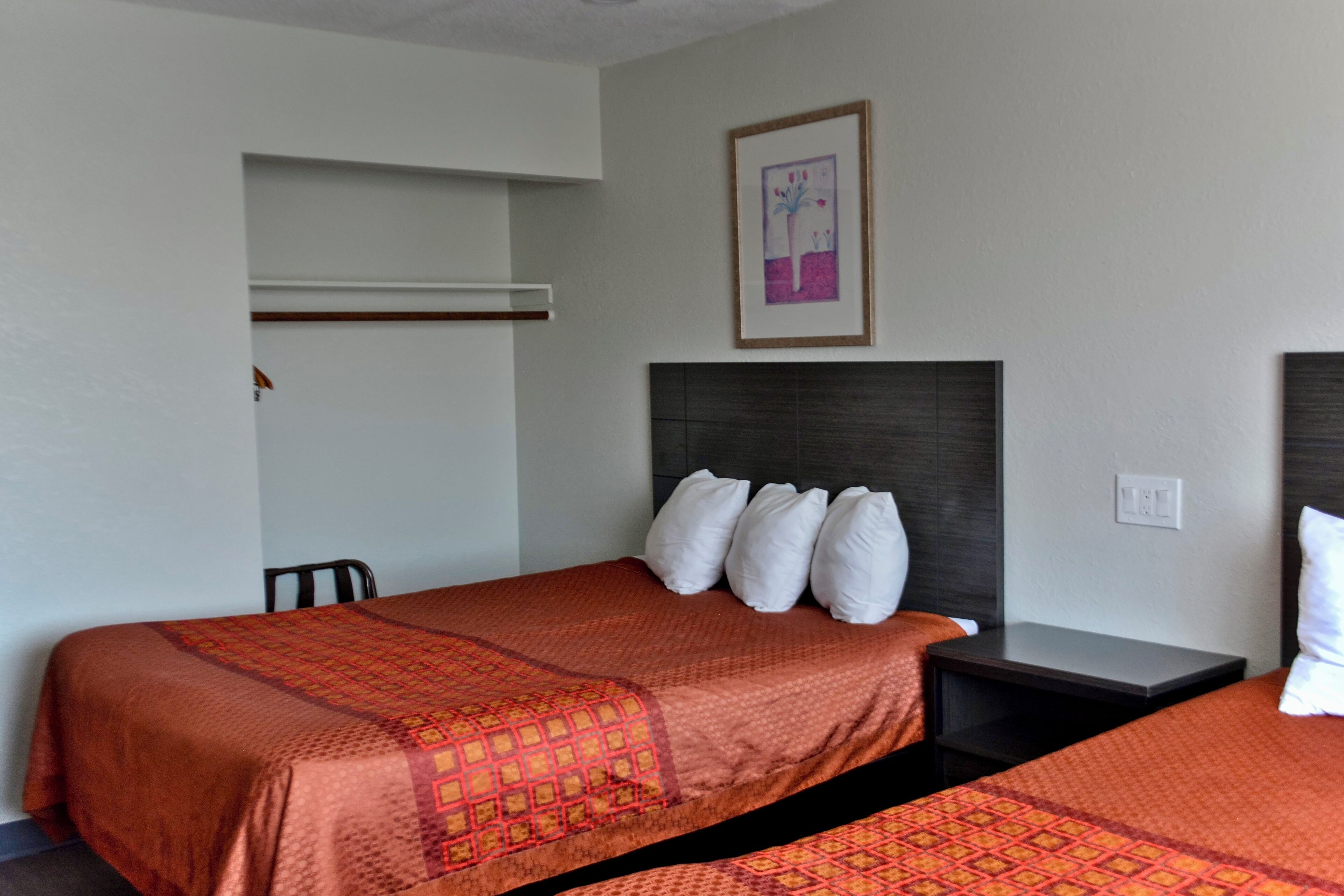 A hotel room with two beds, each with a patterned bedspread, a headboard, and a nightstand.