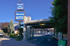 A motel with a stone facade, a covered entrance, and multiple signs including 'Maverick Motel' and 'Vacancy'. - The Maverick Motel, Main Street USA Collection by PNW Hospitality (Klamath Falls)