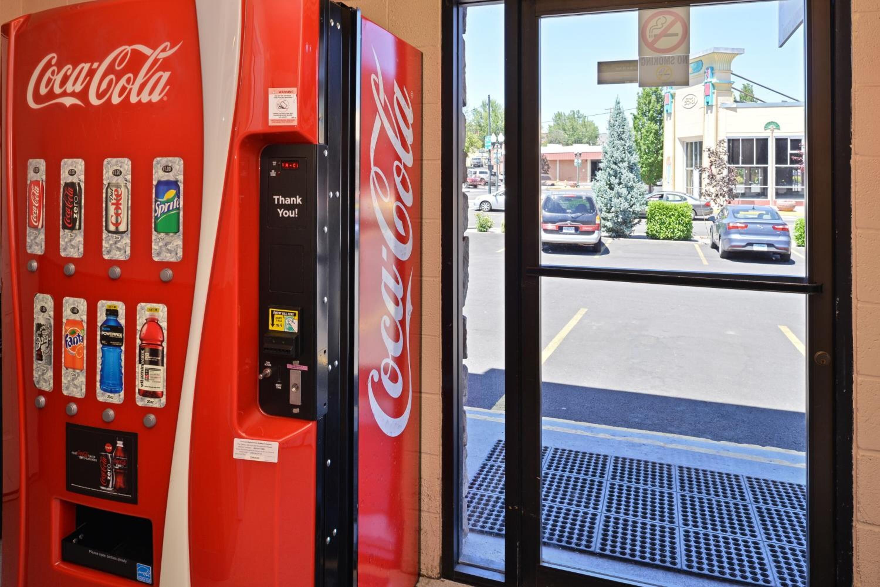 A Coca-Cola vending machine with various drink options and a digital display.