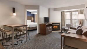 A hotel room with a bed, a TV, a fireplace, a sofa, a desk, and chairs. - Residence Inn by Marriott Buffalo Galleria Mall (Buffalo)