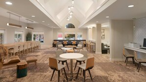A spacious lounge area with a long table, multiple chairs, a round table, and a bar area. - Residence Inn by Marriott Buffalo Galleria Mall (Buffalo)