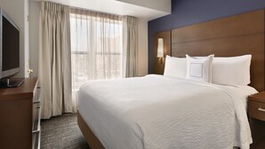 A hotel room with a large bed, a flat-screen TV, a wooden headboard, and a window with curtains. - Residence Inn by Marriott Buffalo Galleria Mall (Buffalo)