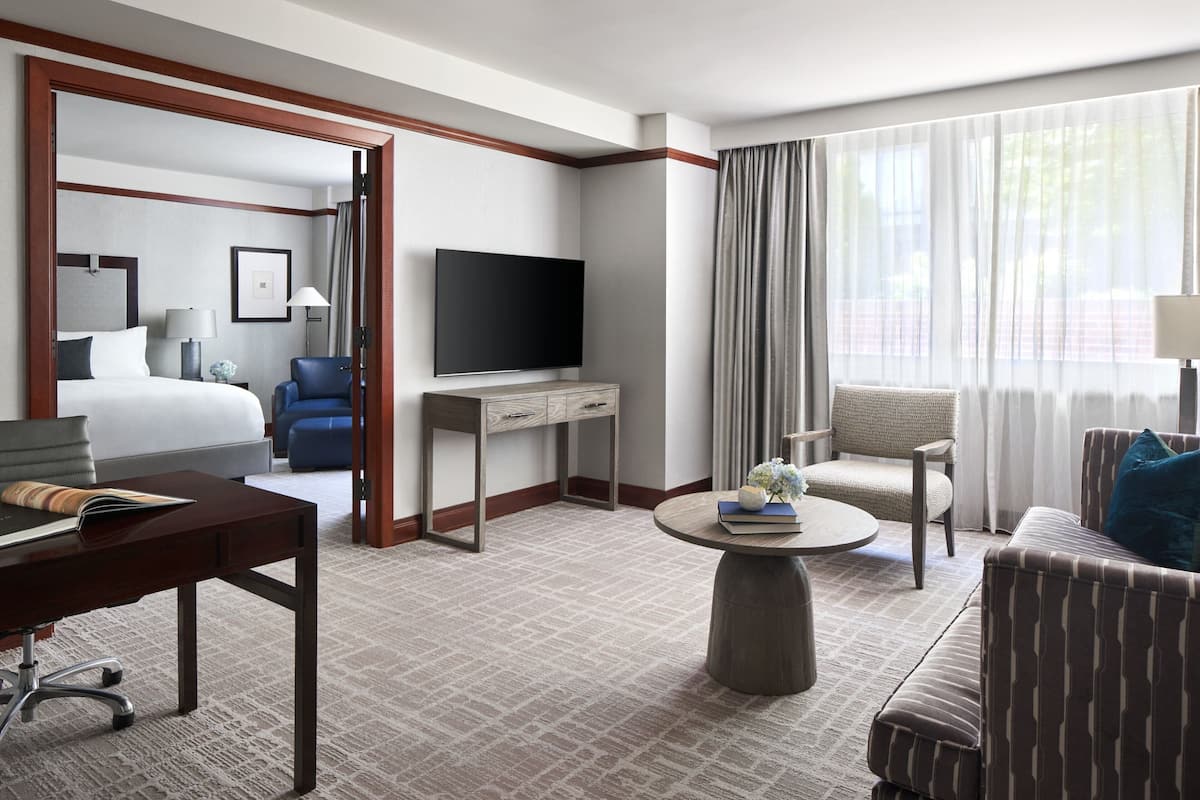 A hotel room with a bed, a desk, a television, a sofa, and a chair.