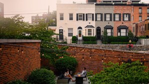 An outdoor patio area with brick walls, string lights, and greenery. - The Ritz-Carlton Georgetown, Washington, D.C. (Washington)