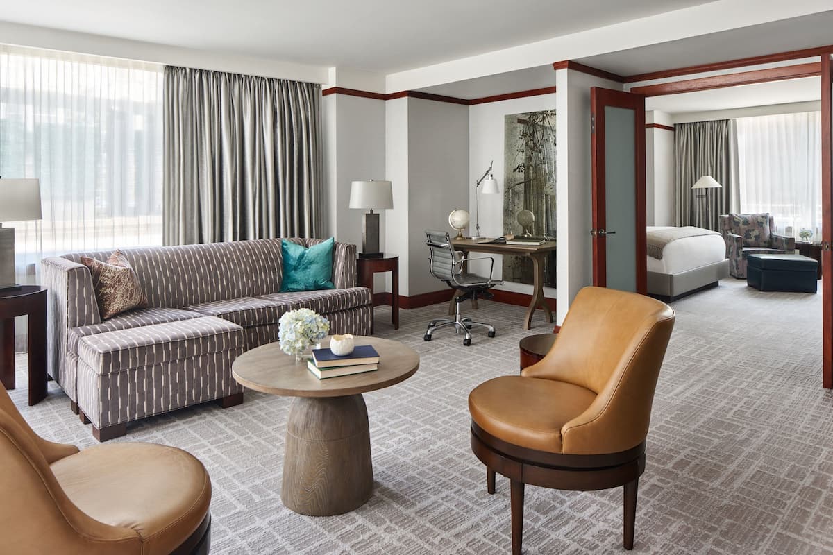 A hotel room with a sofa, armchair, desk, and a bed.