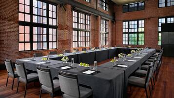 A long conference table set up in a room with brick walls and large windows.