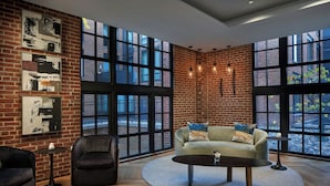A spacious room with large windows, a brick wall, and modern furniture. - The Ritz-Carlton Georgetown, Washington, D.C. (Washington)