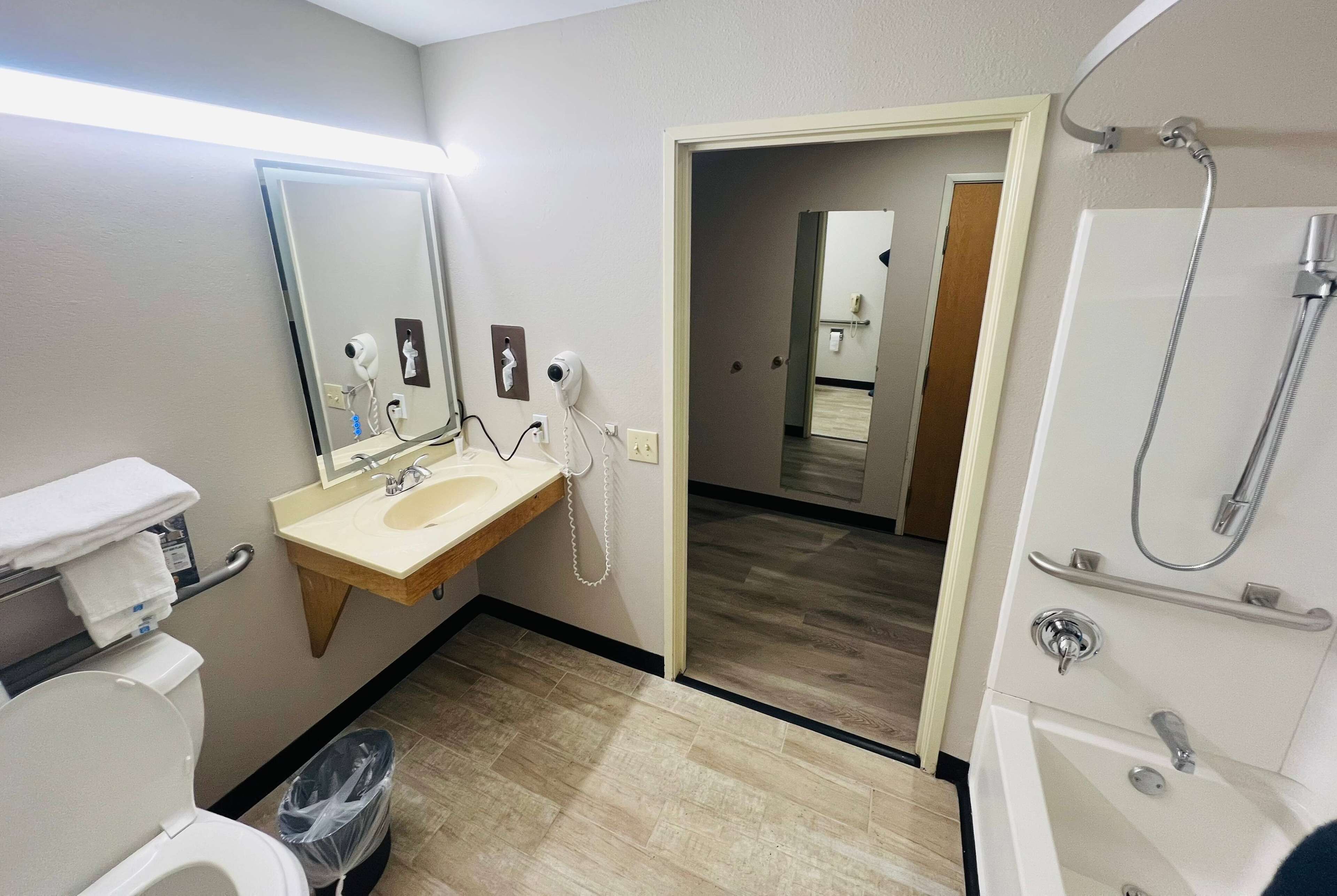 A hotel bathroom with a toilet, sink, mirror, and shower.