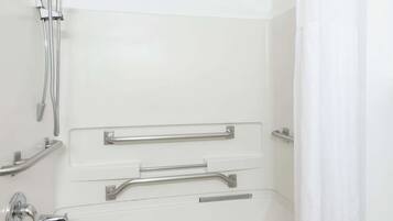Un baño con ducha a nivel, barras de apoyo y cabezal de ducha manual.