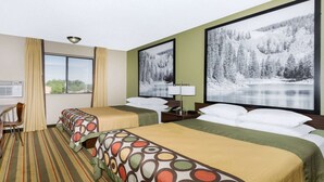 Une chambre d’hôtel avec deux lits, un bureau, une chaise, une fenêtre et un grand tableau encadré représentant un paysage enneigé.