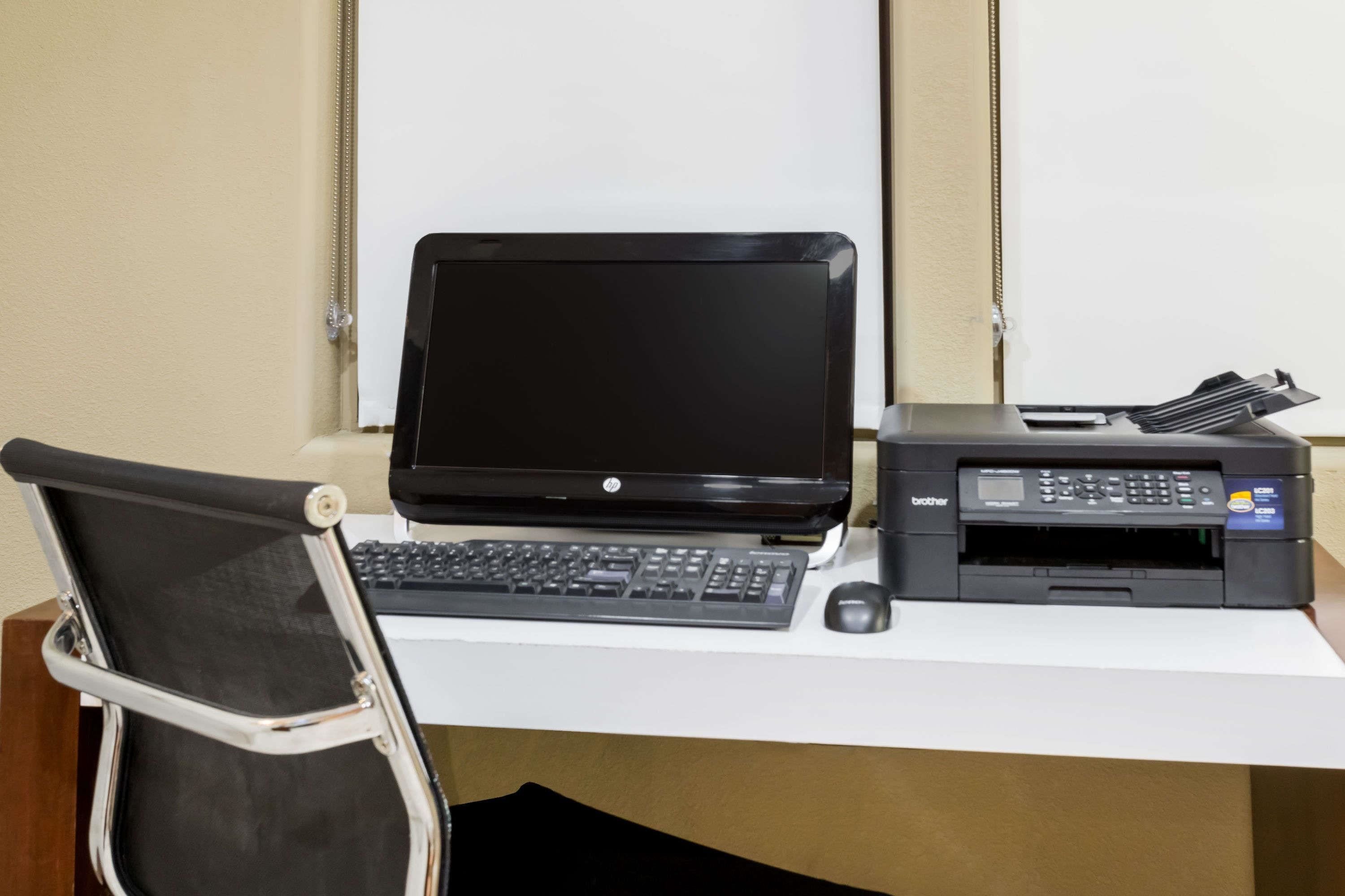 A desk with a laptop, a printer, and a chair.