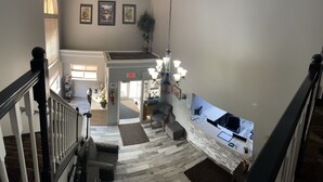 A hotel lobby with a staircase, a reception desk, a chandelier, and framed artwork on the walls. - Adams Inn (Adams)