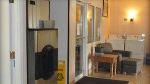 A laundry room with a washing machine, dryer, and a caution sign. - Adams Inn (Adams)