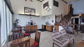 A spacious lobby with wooden furniture, a staircase, and a kitchen area.