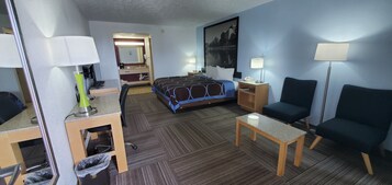 Una habitación de hotel con cama, escritorio, silla y una mesa con lámpara.