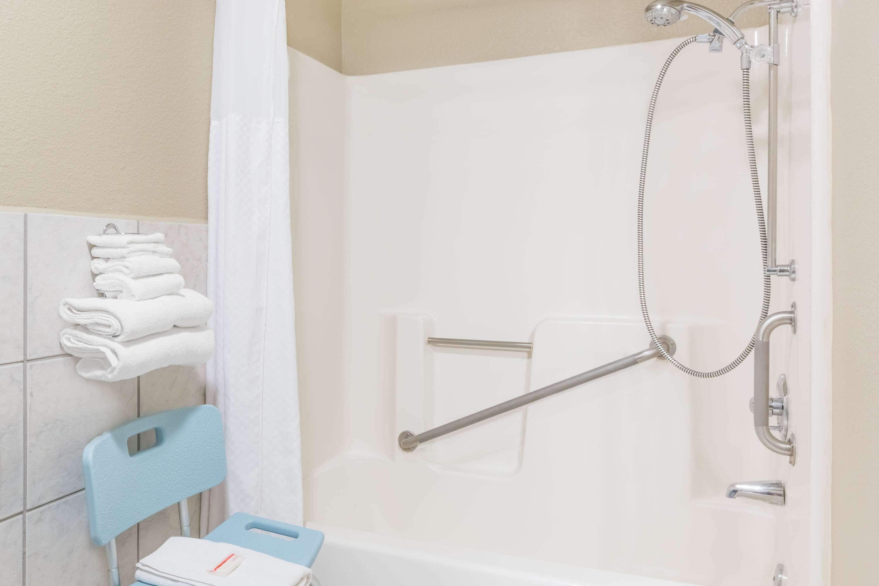 Een badkamer met een douche, een stoel en een stapel handdoeken.