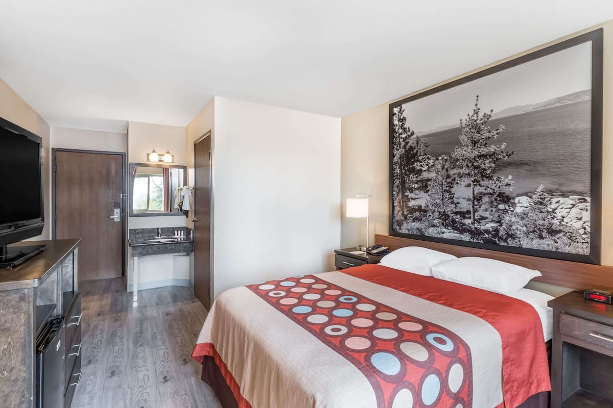 A hotel room with a bed, a TV, a desk, and a bathroom.