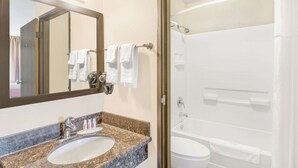 A bathroom with a granite countertop sink, a mirror, and a shower area. - Super 8 by Wyndham Redding (Redding)