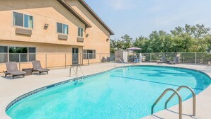 A swimming pool with lounge chairs and a building with multiple windows in the background. - Super 8 by Wyndham Redding (Redding)