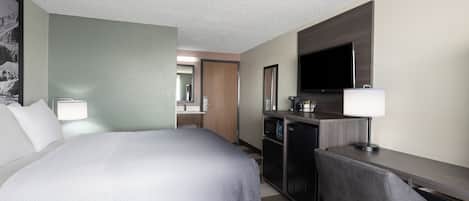 A hotel room with a bed, a desk, a television, and a mirror.
