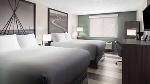 A hotel room with two beds, a desk, a lamp, and a large window. - Super 8 by Wyndham Conrad (Conrad)