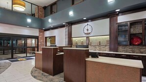A hotel reception area with a clock, a reception desk, and a counter. - Super 8 by Wyndham Conrad (Conrad)