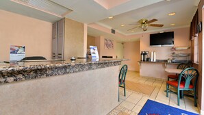 A hotel lobby with a reception desk, a television mounted on the wall, and a ceiling fan. - Anthony Inn (Anthony)