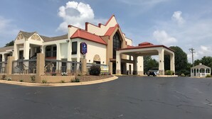 A hotel with a red roof, beige walls, and a covered parking area. - Carolina Inn & Suites of Lake Norman (Mooresville)