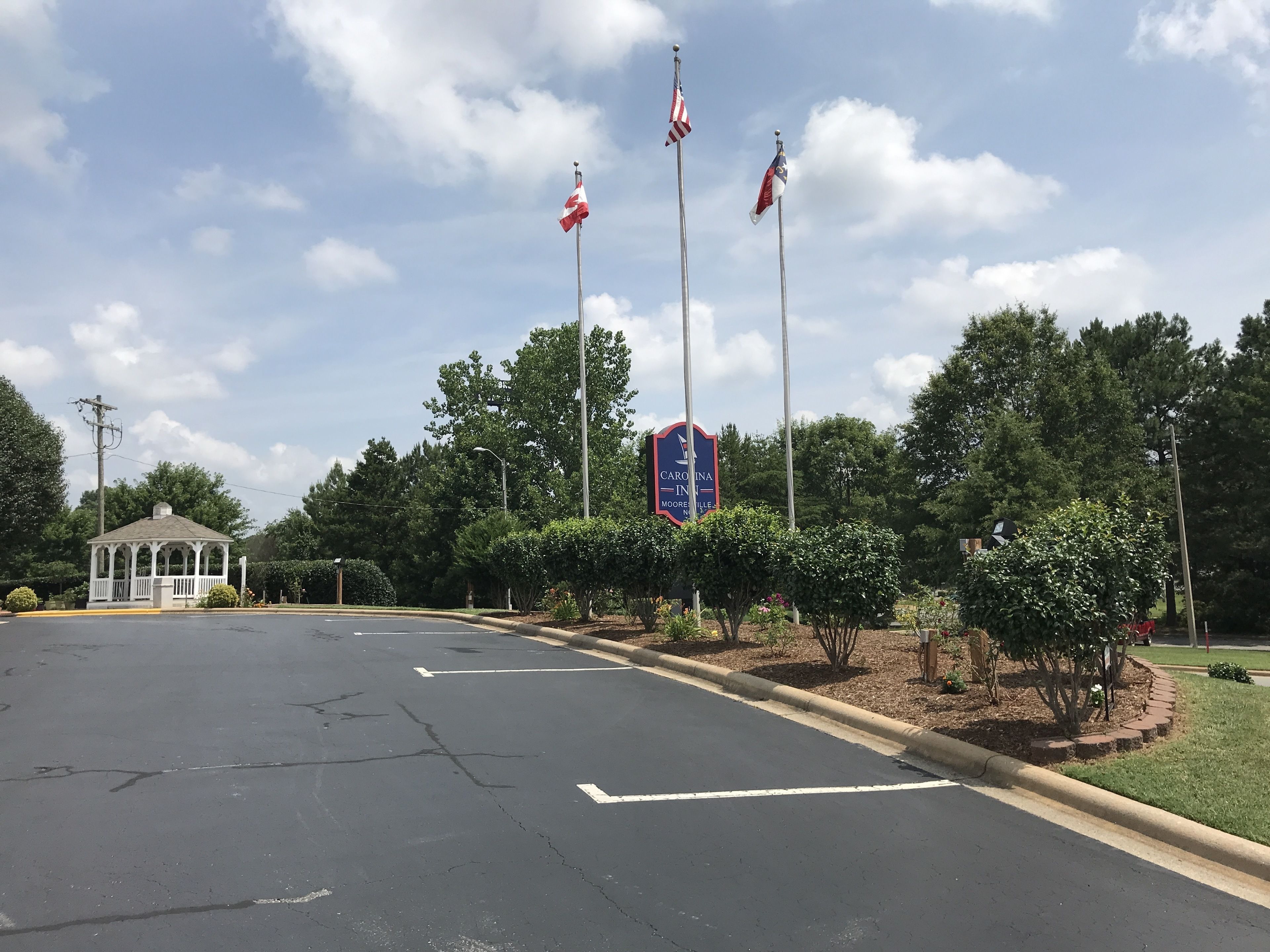 A parking lot with a gazebo, a sign with flags, and a blue sign with text.